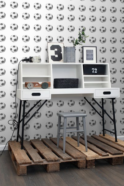 Schreibtisch mit Stuhl und Fußballtapete im Raum.