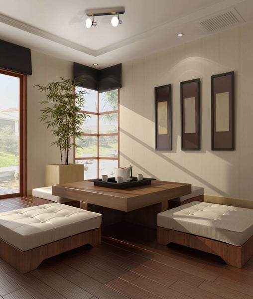 Helles, geräumiges Zimmer mit Holzboden, Tisch, Sitzkissen, Kunstwerken und Zimmerpflanze.