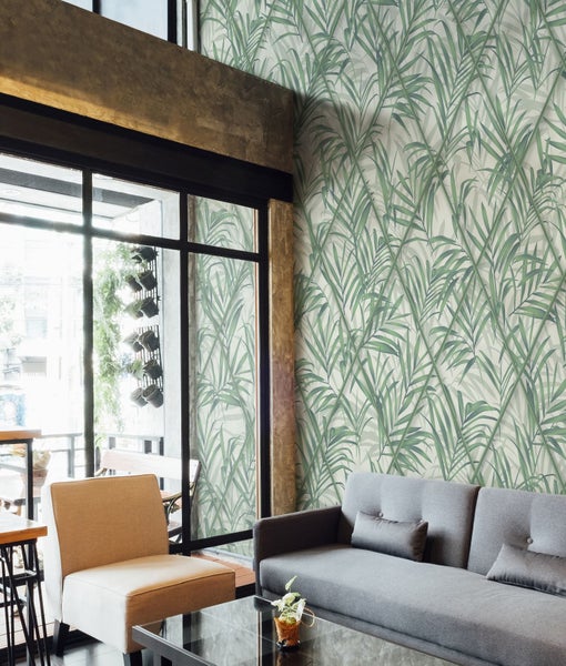 Wohnzimmer mit Sofa, Sessel und Wandtapete mit Blättermotiv für ein stilvolles Ambiente.