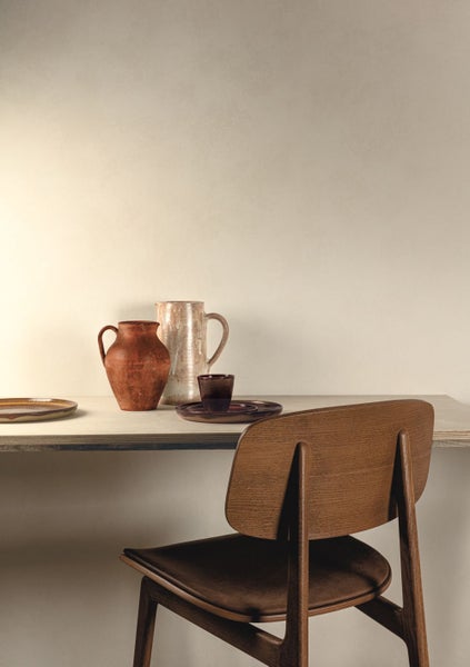 Tischdekoration mit Tonkrügen, Geschirr und Holzstuhl