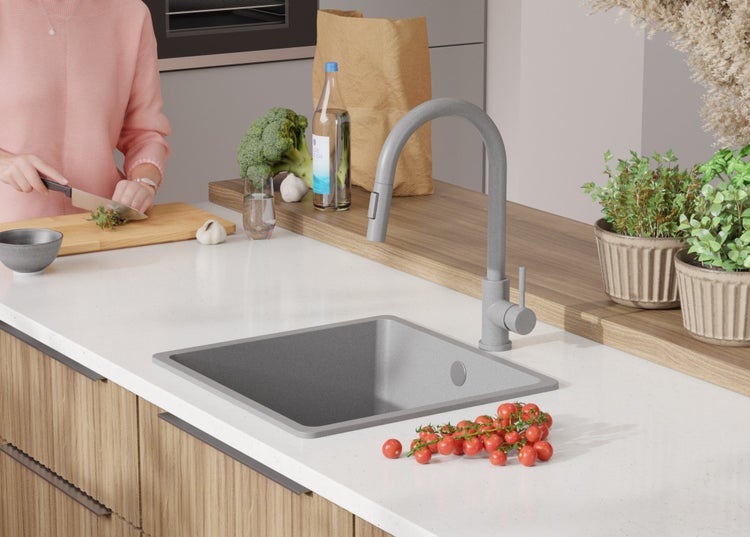 Küchenszene mit Spüle, Armatur, Lebensmitteln und einer Person beim Kochen