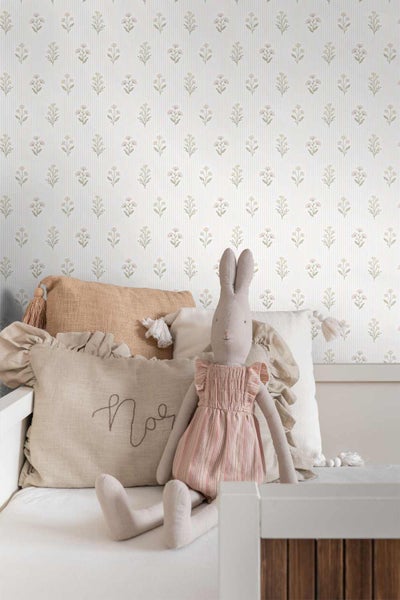 Vliestapete mit Blumenmuster und vertikalen Streifen in einem Kinderzimmer mit Bett und Kissen.
