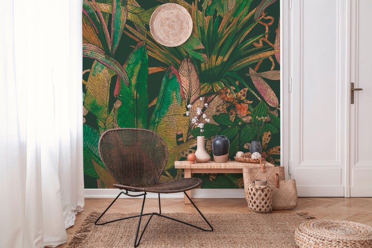Wohnraum mit botanischer Tapete im Dschungel-Design, einem Rattansessel, einer Holzbank mit Dekovasen und einem Juteteppich.