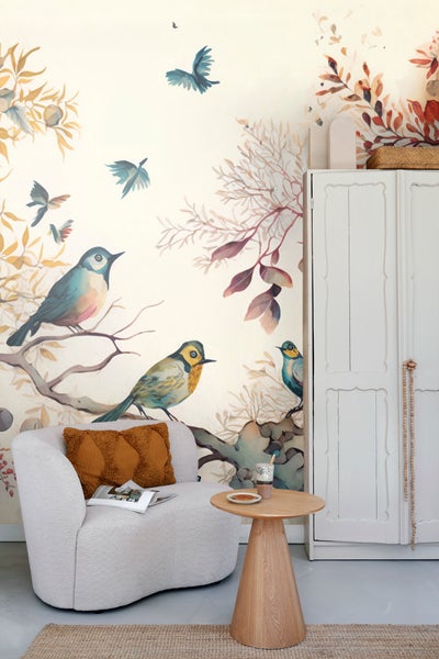 Wohnszene mit Sessel, Tisch und Wandbild mit Vogelmotiven für eine freundliche Atmosphäre