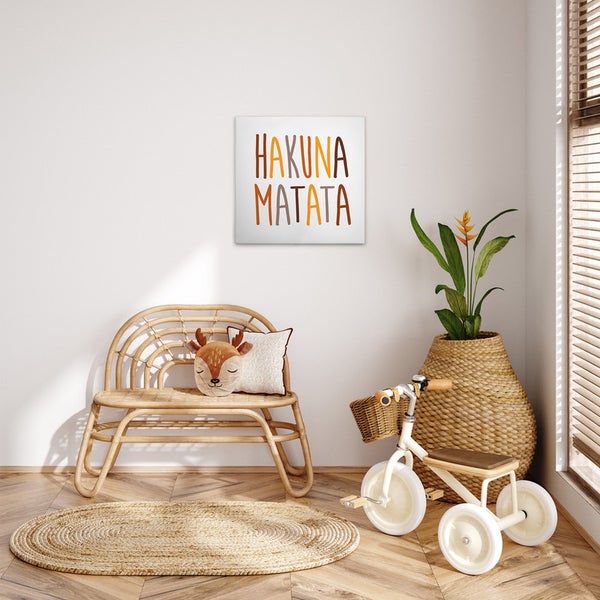 Dekoratives Kinderzimmer mit Hakuna Matata Wandbild, Rattanbank, ovalem Teppich, Dreirad und Pflanze in Flechtvase.