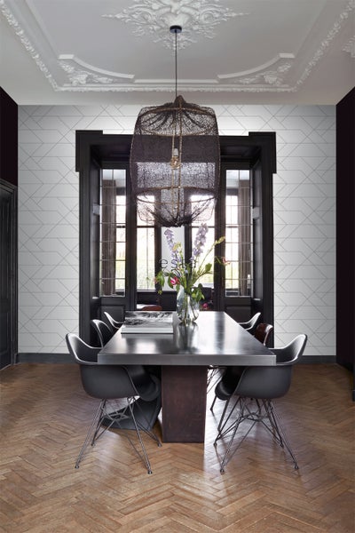 Esszimmer mit Esstisch, Stühlen, Pendelleuchte und geometrischer Tapete.
