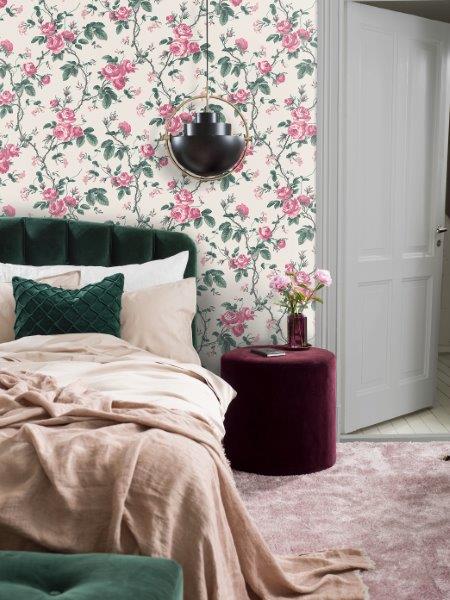 Nahaufnahme einer Wand mit Rosenmuster-Tapete und einem grünen Tuch über einem Stuhl