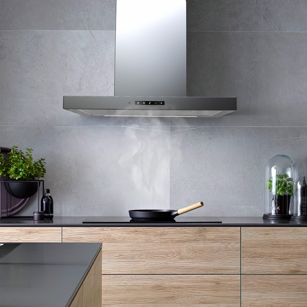 Moderne Dunstabzugshaube in einer hellen Küche mit Holzfronten und einer Pfanne auf dem Kochfeld, von der Dampf aufsteigt.