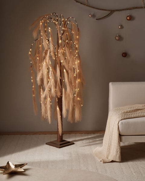 Dekorativer Federbaum mit LED-Beleuchtung neben Sofa und Weihnachtsdekoration