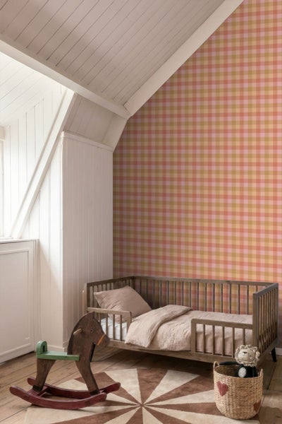 Vliestapete mit Karomuster in einem hellen Kinderzimmer mit Holzbett, Schaukelpferd und weißer Holzvertäfelung an der Dachschräge.