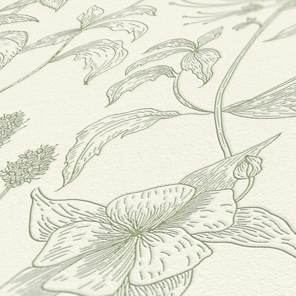 Nahaufnahme eines Zimmers mit einem Schreibtisch, auf dem eine Skulptur, eine Pflanze, eine Tasse und ein Bleistift stehen, vor einer botanischen Tapete