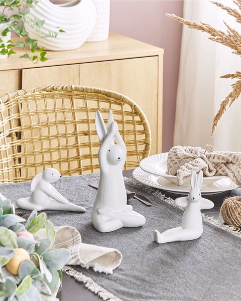 Dekorationstisch mit drei weißen Hasenfiguren in Yoga-Posen