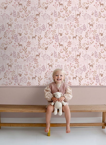 Mädchen vor einer Kinderzimmer-Tapete mit Waldmotiven auf einer Holzbank