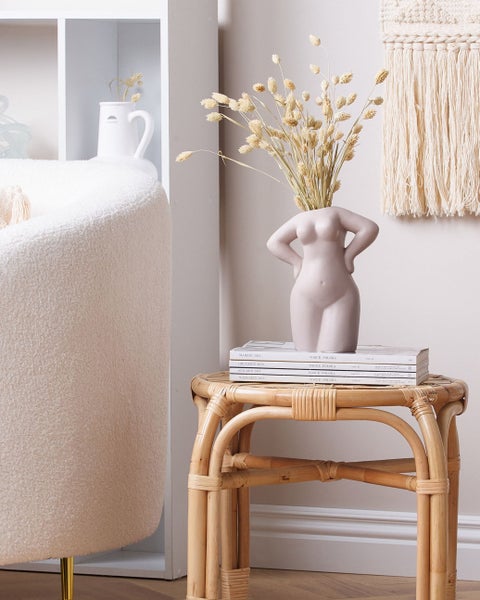 Dekorative Szene mit einem Sessel, einem Rattantisch und einer Blumenvase in Körperform