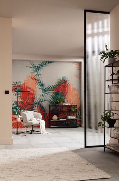 Wohnzimmer mit Sessel, Regal und Wandtapete mit Pflanzenmotiven