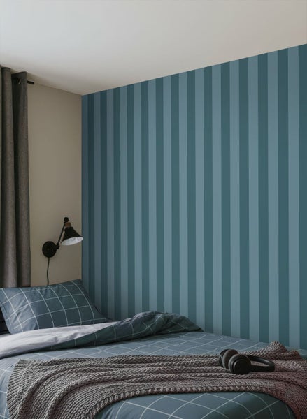 Schlafzimmer mit gestreifter Tapete, Bettwäsche und Strickdecke