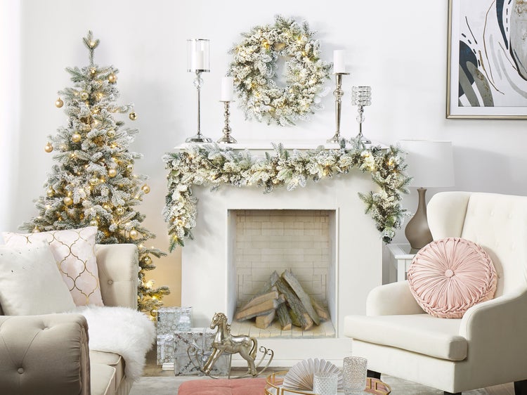 Festlich geschmücktes Wohnzimmer mit Kamin, Weihnachtsbaum, Kranz und Dekorationen.