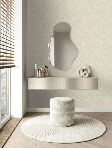 Ein moderner Schminktischbereich mit Tapete mit Palmenmuster, organischem Wandspiegel, schwebender Kommode, gemustertem Hocker und rundem Teppich.