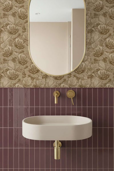 Modernes Badezimmer mit ovalem Waschbecken, wandmontierter Armatur und Spiegel vor einer floralen Tapete und dunklen Fliesen.