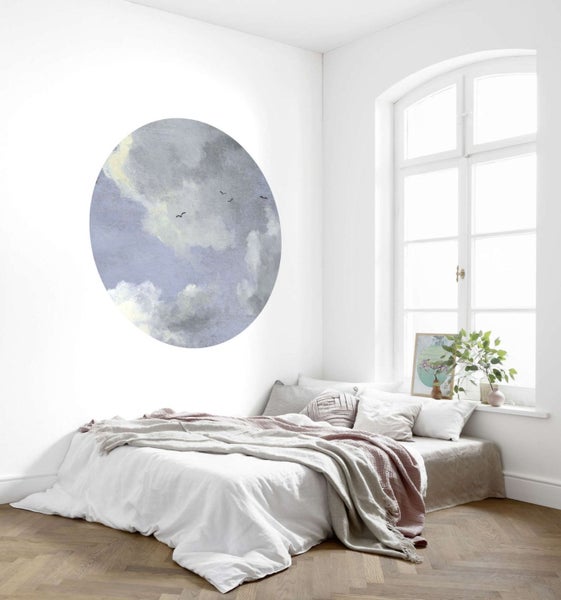 Helles Schlafzimmer mit Bett, Fenster und Wandtattoo mit Wolkenmotiv.