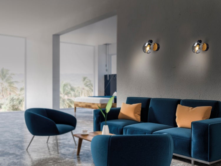 Modernes Wohnzimmer mit blauem Sofa, Sessel und Wandleuchten mit Glaskugeln.