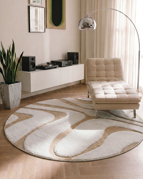 Runder Teppich mit abstraktem Wellenmuster in einem modernen Wohnzimmer mit Lederliege, Bogenlampe und weißem Sideboard.
