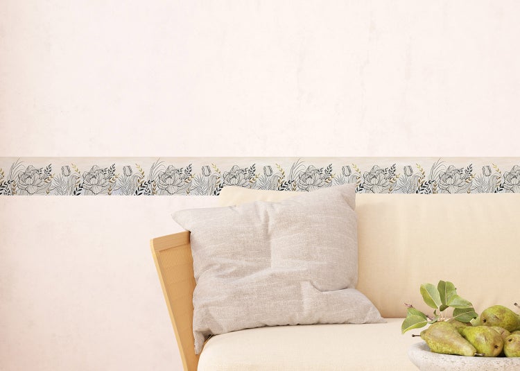 Selbstklebende Tapetenbordüre mit Blumenmuster in einem hellen Wohnzimmer über einem Sofa.