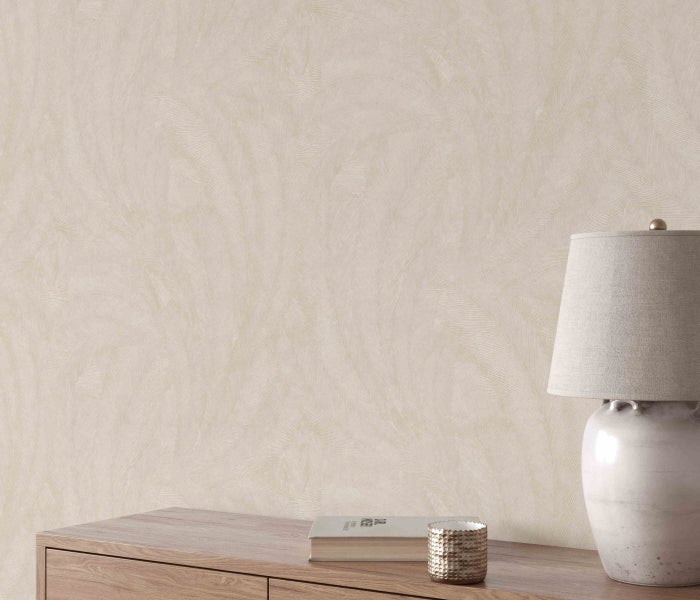 Nahaufnahme einer Wand mit einer dezent gemusterten Tapete, einem Holztisch, einer Lampe, einem Buch und einer Kerze.