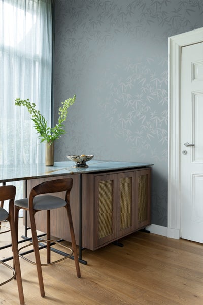 Raumansicht mit Bambusmuster-Tapete, Sideboard und Holzboden