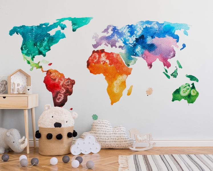 Vliestapete mit Weltkarte im Aquarell-Stil in einem hellen, organisierten Kinderzimmer mit Spielzeug und Holzmöbeln.