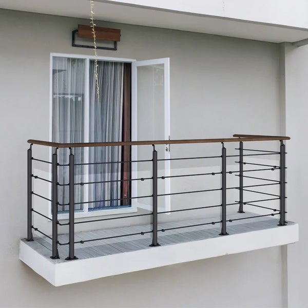 Modernes Balkongeländer mit dunklen Metallpfosten, horizontalen Stahlseilen, Glaselementen und einem Handlauf aus Holz.