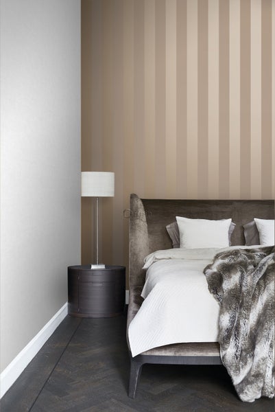 Schlafzimmer mit Bett, Nachttisch und gestreifter Tapete für ein helles Ambiente.