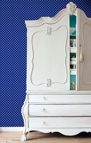 Weißer Schrank mit Schubladen vor einer Wand mit Punktmuster