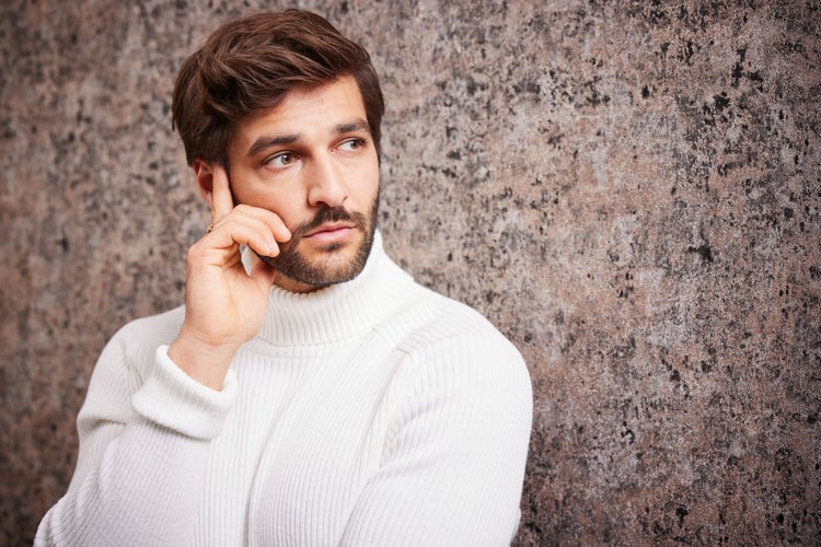 Mann mit Rollkragenpullover vor einer Wand