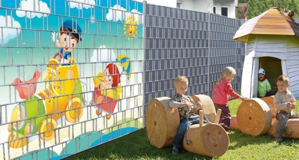 Sichtschutzzaun mit Kindermotiv und spielende Kinder im Garten.