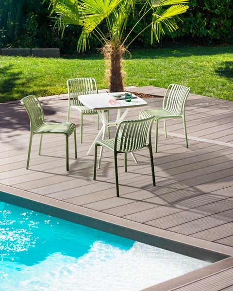 Gartenszene mit Tisch und vier Stühlen auf einer Terrasse neben einem Pool