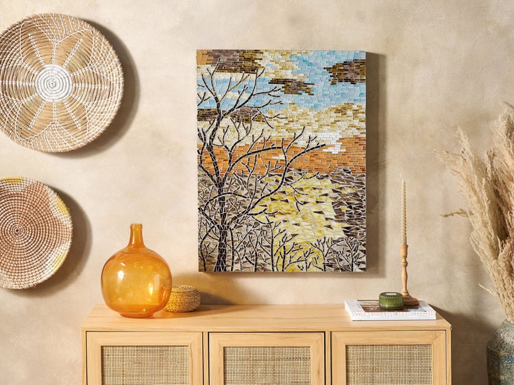 Dekorative Wandgestaltung mit Mosaikbild, Schalen und Kommode im Wohnraum.