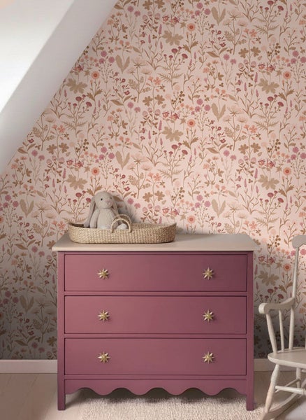 Vliestapete mit floralem Muster in einem Kinderzimmer hinter einer Kommode mit einem Stoffhasen in einem Korb.