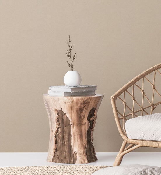 Wohnzimmer-Szene mit Rattan-Sessel, Holzhocker und Teppich