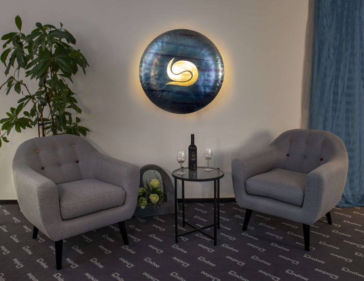 Einladender Loungebereich mit zwei Sesseln, einem Beistelltisch mit Weinflasche und Gläsern sowie einer Wandleuchte.