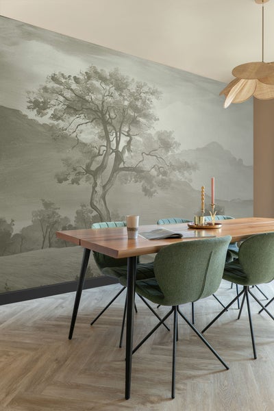 Esszimmer mit Holztisch, grünen Stühlen und einer Wandtapete mit Baumlandschaft