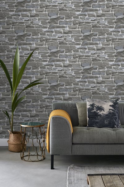 Wohnzimmer mit Steinwandtapete, Sofa, Beistelltisch und Topfpflanze