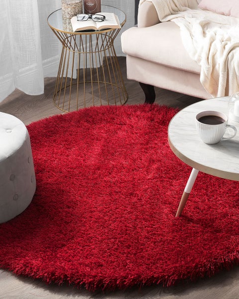 Roter, runder Teppich im Wohnzimmerambiente.