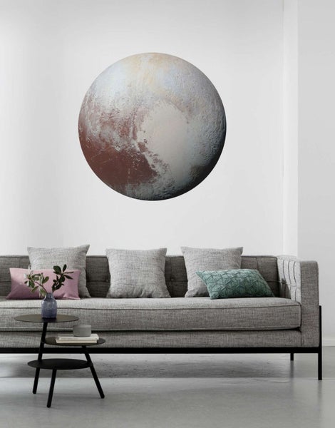 Dekoratives Wandbild von Pluto über einem Sofa in einem Wohnzimmer.