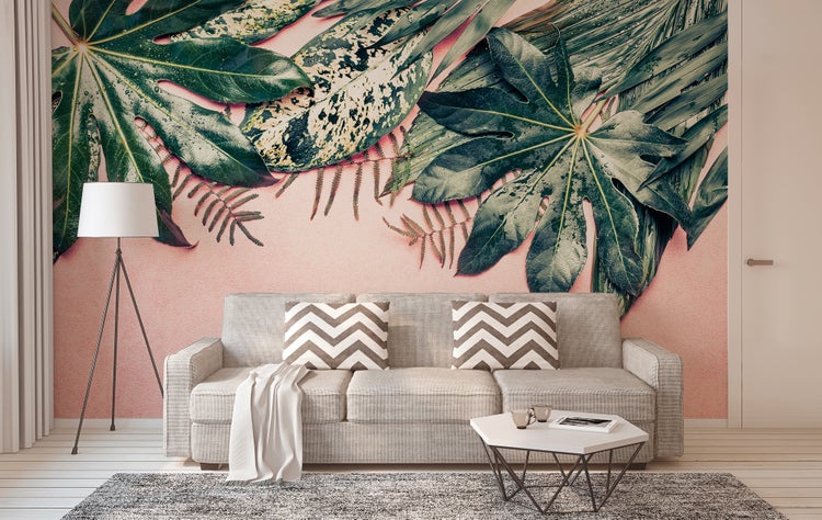 Fototapete mit tropischen Blättern in einem modernen Wohnzimmer mit grauem Sofa, Stehlampe, Couchtisch und Teppich.