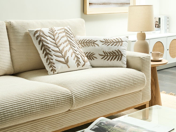 Wohnzimmer mit Cordcouch und dekorativen Kissen mit Pflanzenmotiven