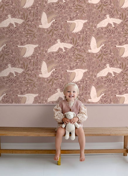 Kinderzimmer mit Tapete mit Schwanenmuster und einem kleinen Mädchen, das auf einer Bank sitzt