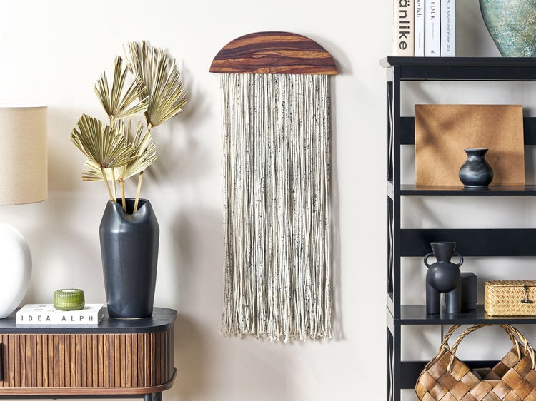 Dekoratives Wandbehang mit Holzdetails und Textilfransen im Wohnzimmer