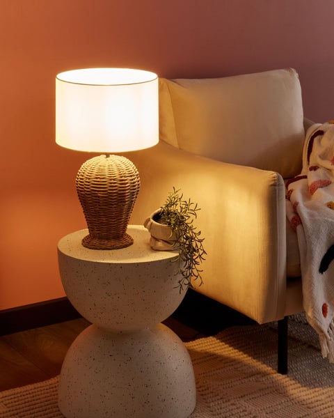 Dekorative Szene mit Korblampe auf Beistelltisch und Sessel