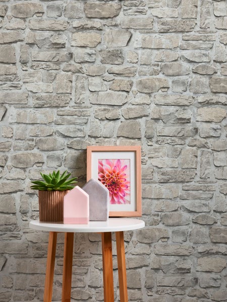 Dekorative Steinwand mit Tisch, Pflanze und Bilderrahmen